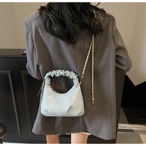 Détail du sac à main bleu clair avec poignée plissée et chaîne dorée sur mannequin
