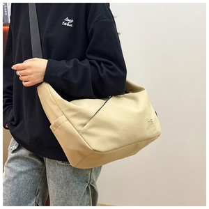 Detail of minimalist beige nylon crossbody bag with MS logo shown on model
