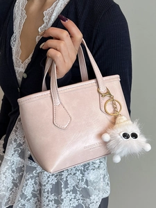 Elegant pale pink leather bucket bag with a white plush pompom charm and fashion handle