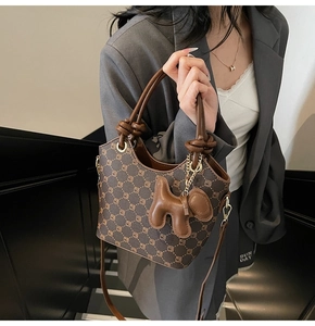 Vue détaillée d'un sac seau marron à monogramme avec un pendentif en cuir en forme de chien