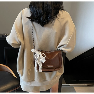 Brown leather crossbody bag with silver chain strap and white lace bow detail