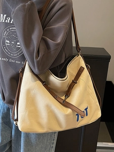 Minimalist canvas tote bag with brown leather straps and blue TOT embroidery