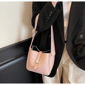Detail view of pink lychee texture bucket bag with silver buckle on black suit