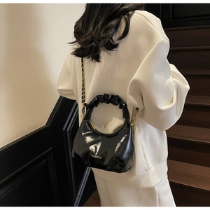 Vue détaillée du sac à main noir froncé porté par un mannequin dans un décor minimal