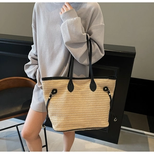Detail of contrast leather straps and woven straw texture on large tote bag