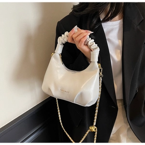 Vue détaillée du sac hobo blanc plissé avec logo doré et bandoulière en chaîne chic