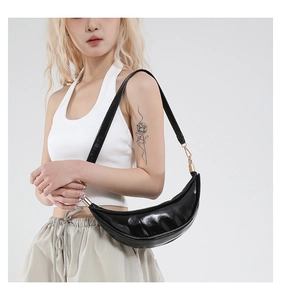 Close-up of black crescent shoulder bag with glossy leather texture and gold hardware details