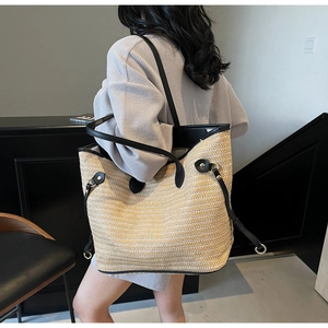 Detailed close-up of straw woven texture with black leather trim on a large tote bag