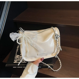 Detailed close-up of cream soft leather handbag with pearl bow and lace stitching detail