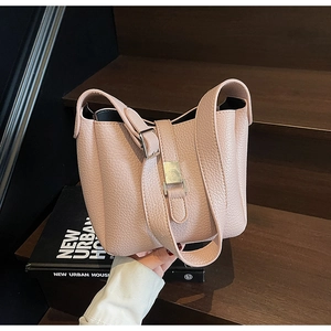 Detailed view of pink lychee grain leather texture and gold buckle on a stylish tote bag