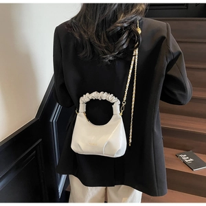 Sac croissant blanc brillant avec anse plissée et bandoulière porté par un mannequin