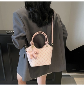 Sac seau rose clair avec texture losange, poignées rondes et charm chien sur modèle