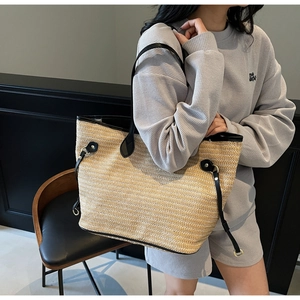 Close-up of contrast woven straw tote with black leather trim and gold metal accents