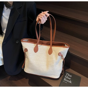 Detail of woven straw tote bag featuring contrast brown leather trim and handles