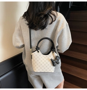 Détail du sac seau à carreaux blanc cassé avec poignée noire et pendentif ours