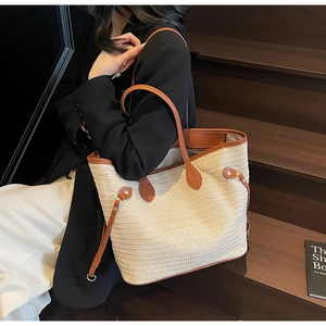 Close-up of contrast color straw woven tote with leather straps on a wooden staircase