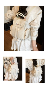 Detail of cream canvas backpack with flap drawstring closure and colorful MeaRey embroidery
