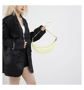 Detail of light yellow crescent shoulder bag with smooth texture and golden metal hardware