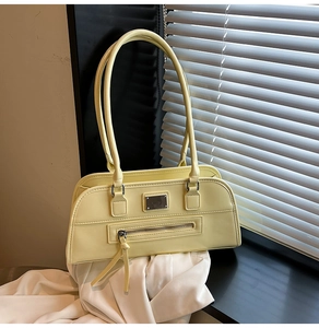 Détail d'un sac à bandoulière rétro jaune crème avec plaque argentée et fermetures éclair