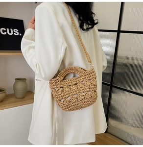 Detail of hand-woven beige straw bucket bag with thick rope texture and crossbody strap