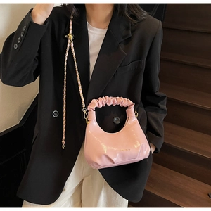 Détail du sac à main rose brillant avec poignée froncée et lettrage doré élégant