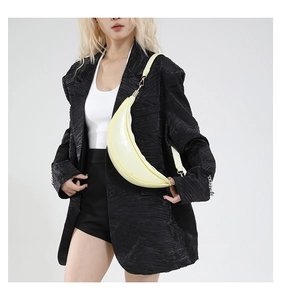 Detail of light yellow crescent crossbody bag with smooth finish and wide strap on model