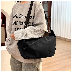 Detail of minimalist black nylon crossbody bag with wide strap and diagonal zipper pocket