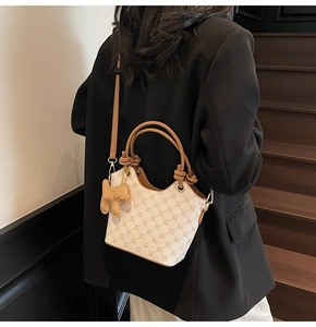 Détail du sac seau imprimé avec breloque chiot et bandoulières en cuir marron