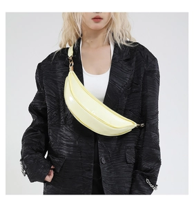 Close-up of yellow glossy crescent bag with golden hardware on a black blazer