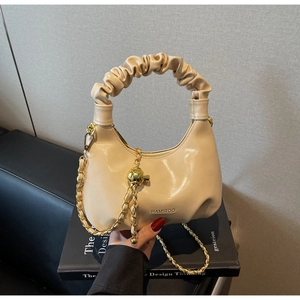 Détail du sac à main plissé beige avec bandoulière tressée et bille métallique décorative