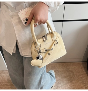 Détail du sac beige avec lettrage tendance et breloque cœur sur une chaîne argentée