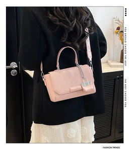 Detailed close-up of a pink textured square bag featuring a metal chain lock charm