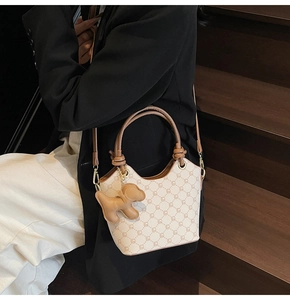 Détail d'un sac seau vintage avec motifs géométriques et breloque chien porté par un mannequin