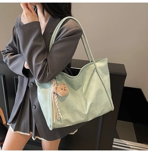Close-up of mint green soft leather tote bag featuring a cute plush bear charm detail