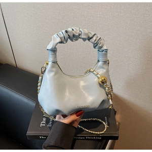 Détail du sac nuage plissé bleu clair avec chaîne à billes dorées et logo de marque