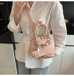 Détail du sac bandoulière rose en forme de coquillage avec chaîne argentée et pendentif cœur