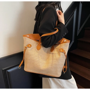 Detail of straw tote bag with brown leather trim and side drawstring on female model