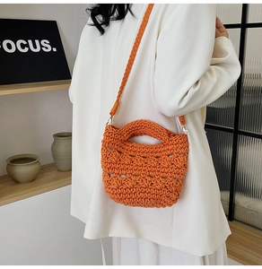 Close-up of bright orange woven handbag featuring a braided strap and thick rope texture