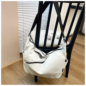 Close-up of white oversized nylon crossbody bag featuring black zippers and MG logo