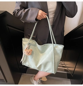 Detailed texture of mint green faux leather tote bag with a brown plush bear charm