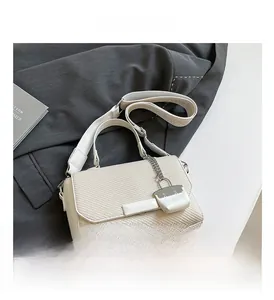 Detail showing cream woven texture, magnetic closure, and adjustable patterned strap on handbag