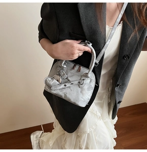 Détail du sac argenté à texture marbrée avec logo mode et pendentif en forme de cœur