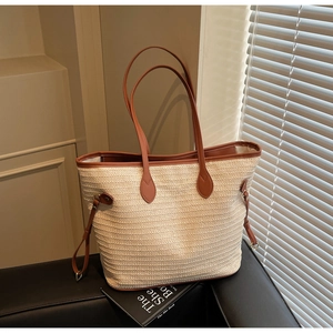 Detail of contrast straw tote bag with brown leather handles and wavy woven texture