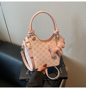Détail du sac seau rose imprimé avec breloque chiot et poignée à nœud élégante