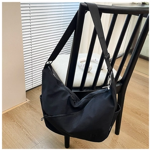 Detail view of black canvas crossbody bag with multi-zipper pockets and wide nylon strap