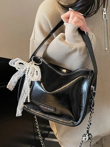 Glossy black pillow shoulder bag with lace bow pendant and silver chain strap