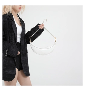 Detail of white moon bag with golden buckles worn over a textured black suit jacket