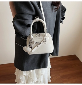 Vue détaillée d'un sac à main blanc en forme de coquillage avec chaîne et pendentif cœur
