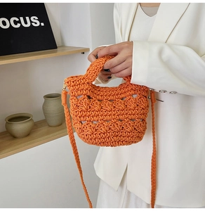 Detail of hand-woven orange bucket bag with hollow mesh texture and shoulder strap
