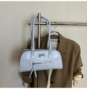 Détail du sac à épaule en cuir bleu clair avec logo argenté sur un cintre en métal